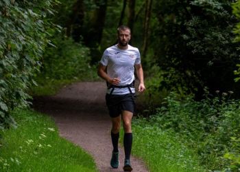 Darren Blanks running down a woodland path. He is wearing a running belt, a white t-shirt and black shorts.